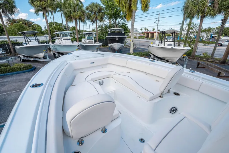 Slide: The Image of 2025 Sea Hunt Ultra 255 SE boat with spacious seating, parked among palm trees. - 26