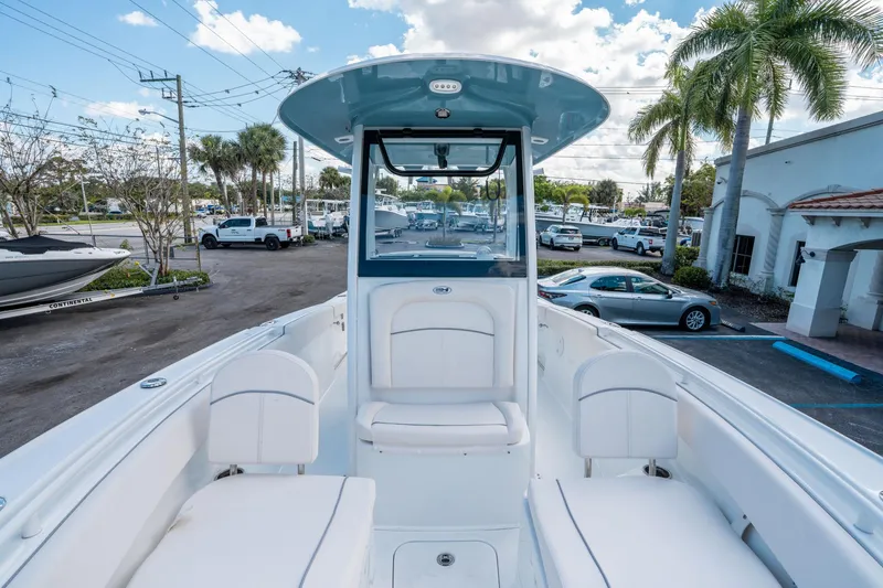 Slide: The Image of 2025 Sea Hunt Ultra 255 SE boat interior with white seating and console, parked outdoors. - 27