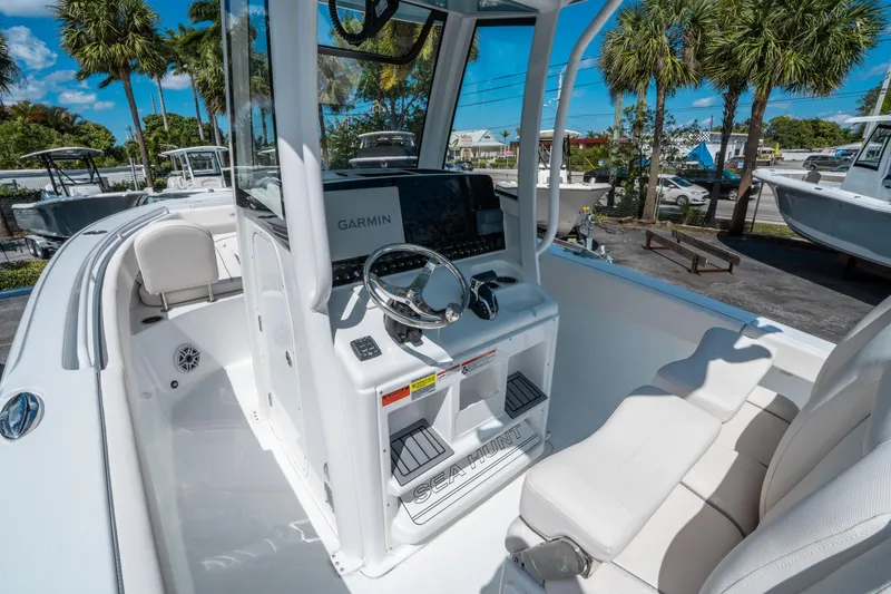 Slide: The Image of 2025 Sea Hunt Ultra 255 SE boat interior with Garmin navigation, white seating, and palm trees in background. - 19