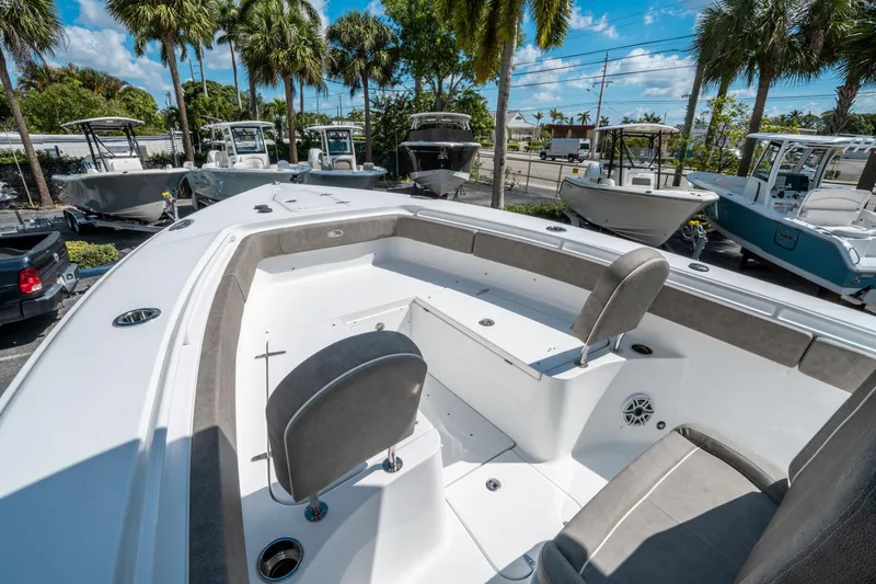 Slide: The Image of 2025 Sea Hunt Gamefish 27 FS boat interior with seating, surrounded by palm trees and other boats. - 35