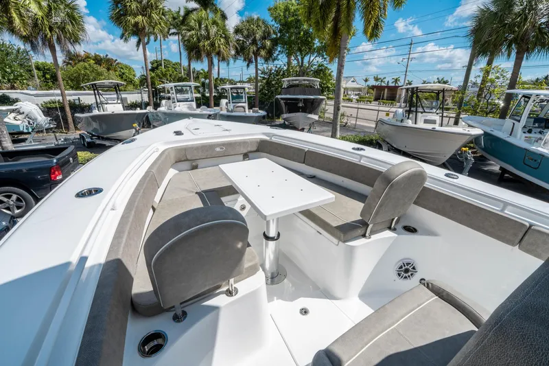 Slide: The Image of 2025 Sea Hunt Gamefish 27 FS boat interior with seating and table, surrounded by palm trees. - 34