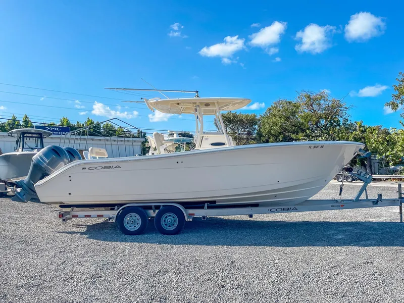 Slide: The Image of 2016 Cobia 277 CC boat on trailer under clear blue sky. - 1