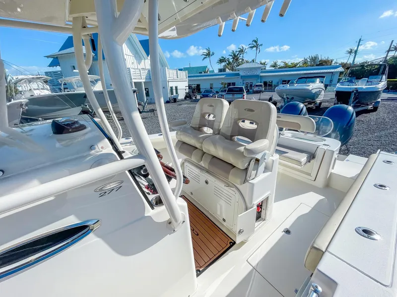 Slide: The Image of 2016 Cobia 277 CC boat interior with seating and controls, docked under clear blue sky. - 13