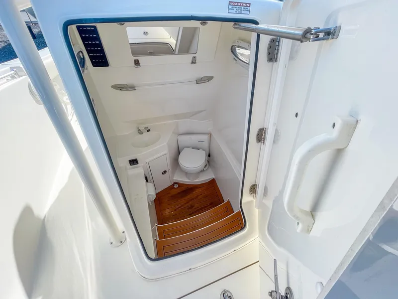 Slide: The Image of 2016 Cobia 277 CC boat interior with compact bathroom and wooden flooring. - 19