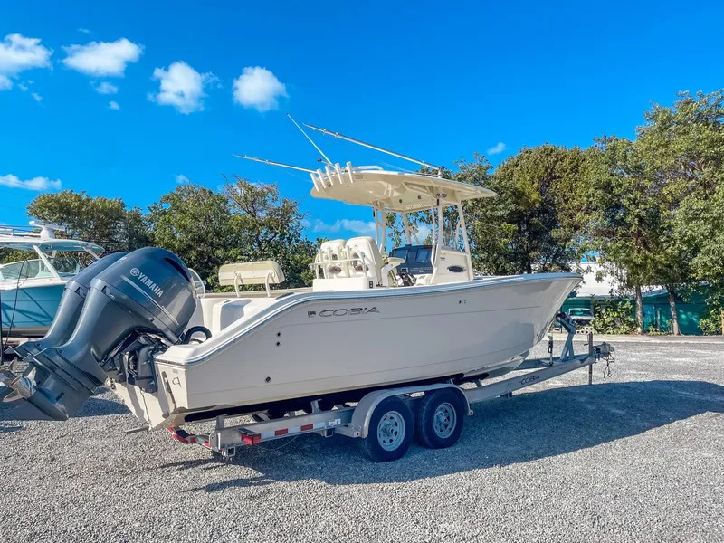 Slide: The Image of 2016 Cobia 277 CC boat on trailer with Yamaha engine, parked outdoors. - 2