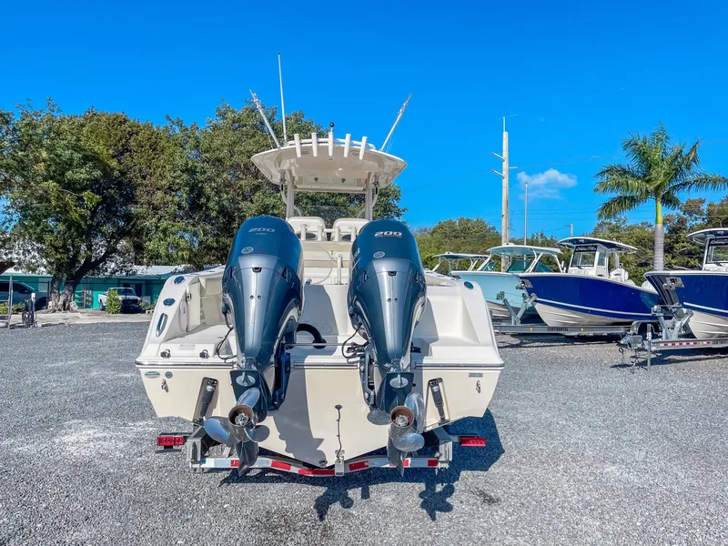 Slide: The Image of 2016 Cobia 277 CC boat with dual outboard engines, parked on gravel lot. - 3