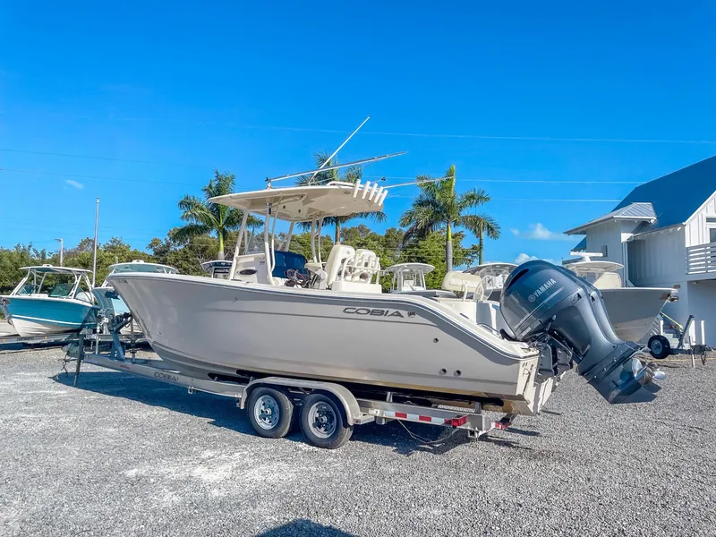 Slide: The Image of 2016 Cobia 277 CC boat on trailer, parked outdoors under clear blue sky. - 4
