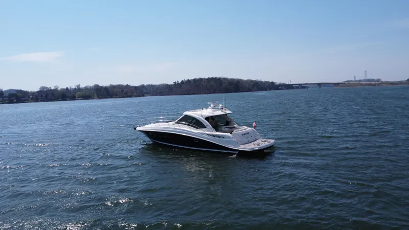 Slide: The Image of 2006 Sea Ray 48 Sundancer yacht cruising on a serene lake under a clear blue sky. - 15