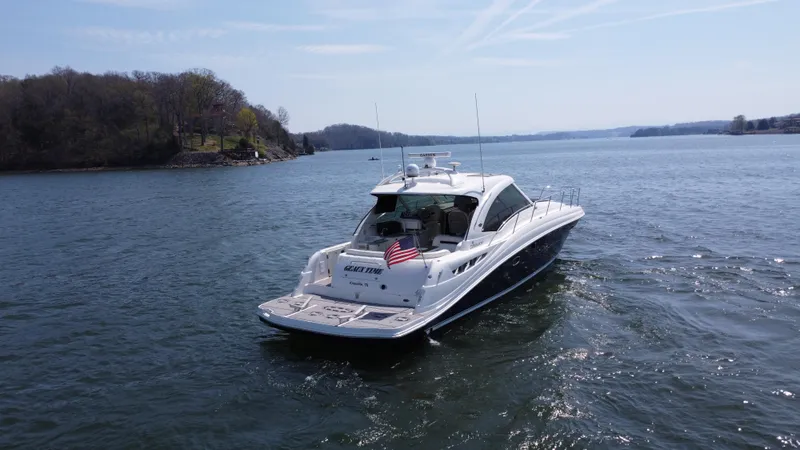 Slide: The Image of 2006 Sea Ray 48 Sundancer yacht cruising on a serene lake with scenic shoreline. - 16