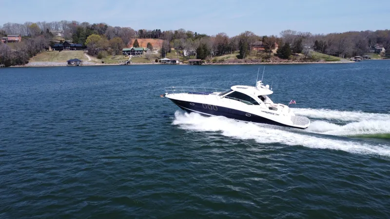Slide: The Image of 2006 Sea Ray 48 Sundancer cruising on a scenic lake with shoreline in the background. - 2
