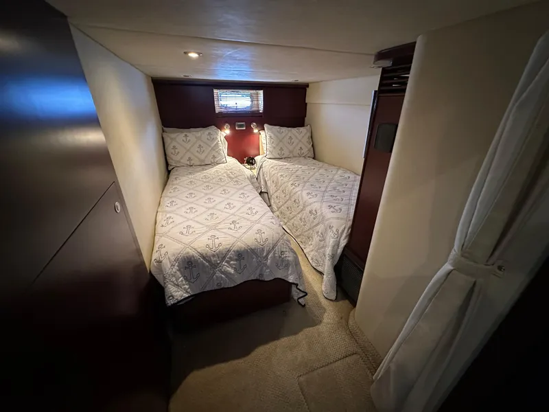 Slide: The Image of 2006 Sea Ray 48 Sundancer cabin with twin beds and nautical-themed bedding. - 30