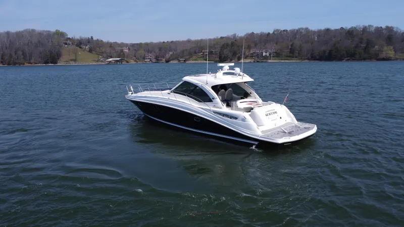 Slide: The Image of 2006 Sea Ray 48 Sundancer yacht on a serene lake with wooded shoreline. - 5