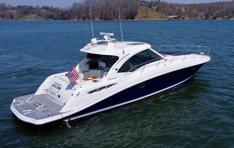 Slide: The Image of 2006 Sea Ray 48 Sundancer yacht cruising on a serene lake with scenic background. - 6