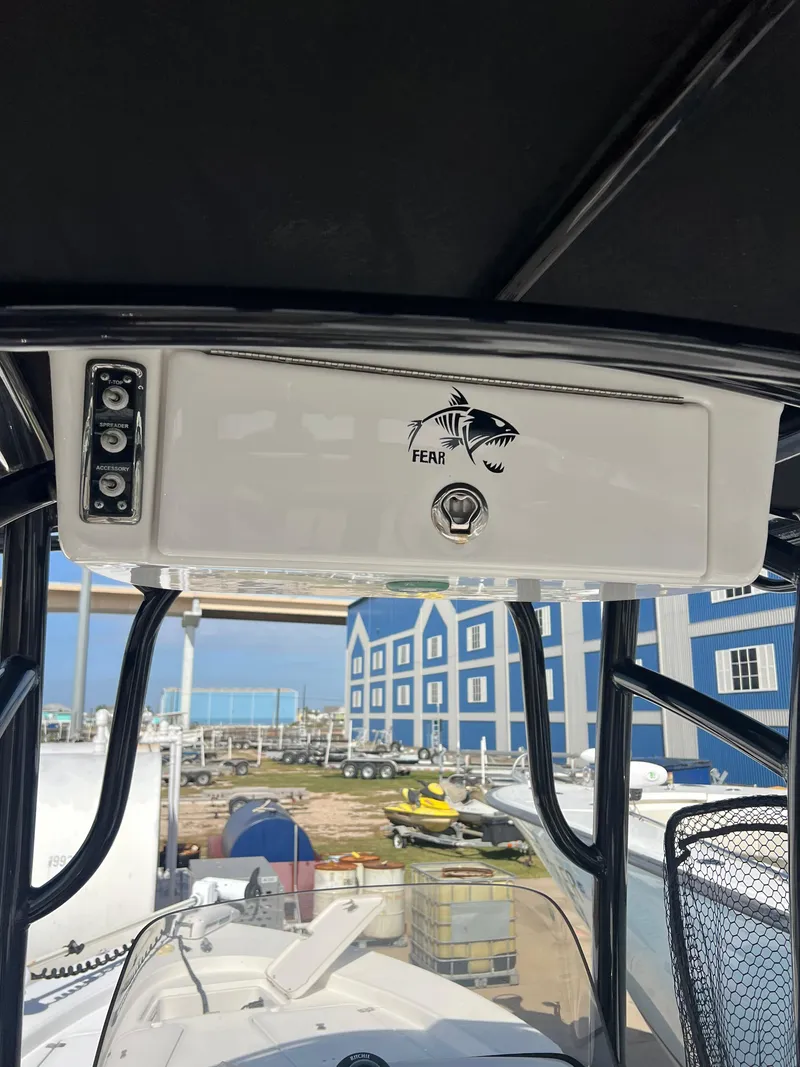 Slide: The Image of 2014 Sportsman Masters 247 Bay Boat console with fish decal, docked near blue buildings. - 21