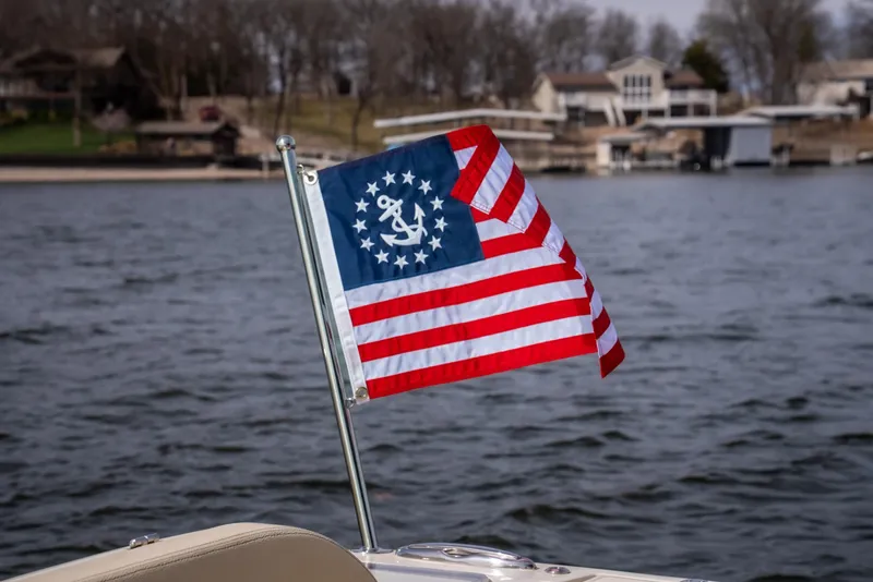 Slide: The Image of 2024 Chris-Craft Calypso 35 CP with nautical flag on lake, houses in background. - 14