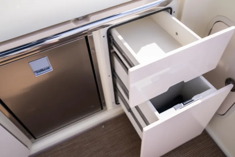 Slide: The Image of 2024 Chris-Craft Calypso 35 CP interior with open drawers and stainless steel fridge. - 18