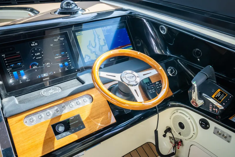 Slide: The Image of 2024 Chris-Craft Calypso 35 CP dashboard with wooden steering wheel and modern navigation displays. - 20