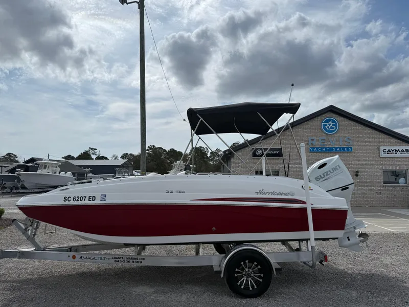Slide: The Image of 2023 Hurricane SunDeck Sport 188 OB boat on trailer, red and white, parked outdoors. - 1