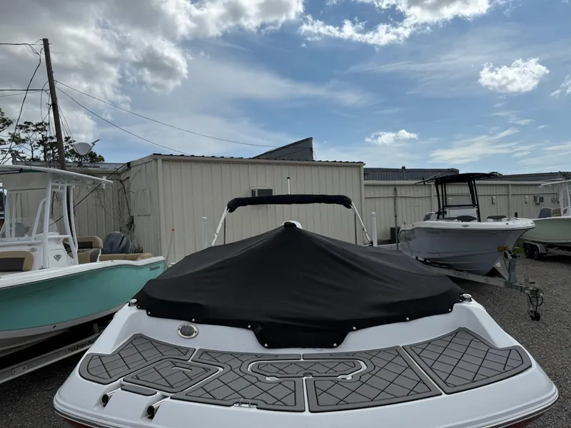 Slide: The Image of 2023 Hurricane SunDeck Sport 188 OB boat with cover, parked outdoors under a cloudy sky. - 10