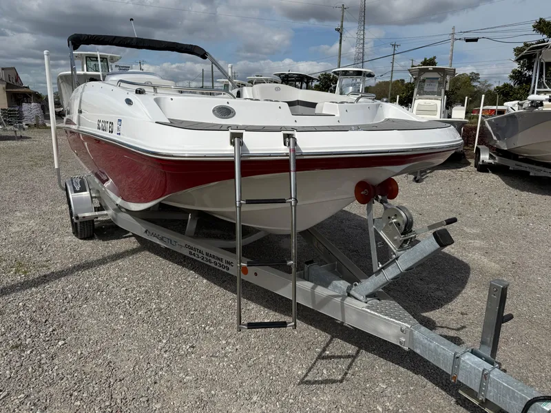 Slide: The Image of 2023 Hurricane SunDeck Sport 188 OB boat on trailer, red and white design, parked outdoors. - 16
