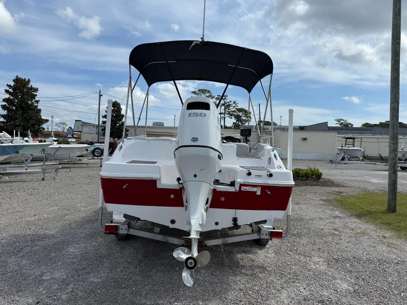 Slide: The Image of 2023 Hurricane SunDeck Sport 188 OB boat with outboard motor and canopy, parked on gravel. - 4