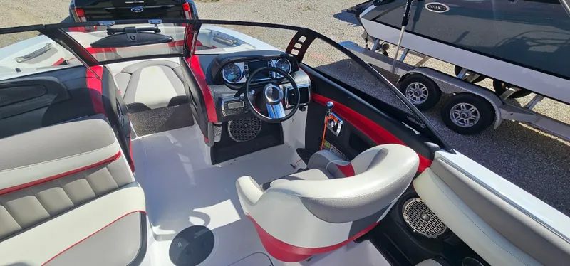 Slide: The Image of 2013 Malibu Wakesetter 23 MXZ boat interior with red and gray seating, steering wheel, and dashboard. - 22