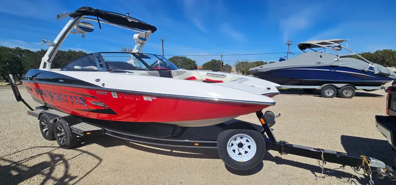 Slide: The Image of 2013 Malibu Wakesetter 23 MXZ boat on trailer, red and white design, parked outdoors. - 4