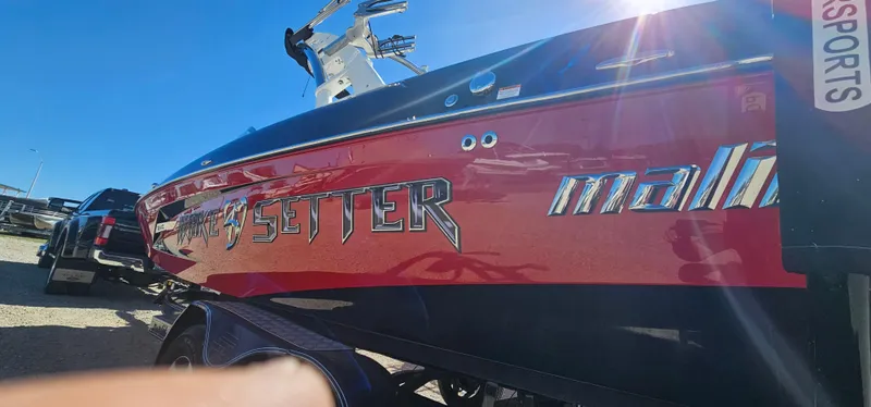 Slide: The Image of 2013 Malibu Wakesetter 23 MXZ boat with red and black exterior in sunlight. - 6