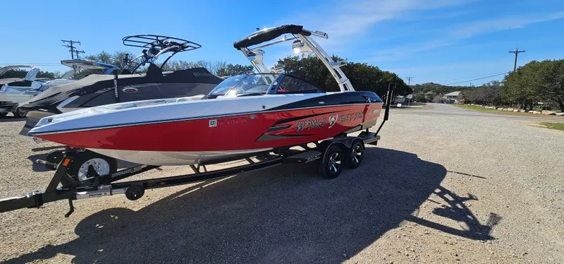 Slide: The Image of 2013 Malibu Wakesetter 23 MXZ boat in red and white on a trailer. - 7