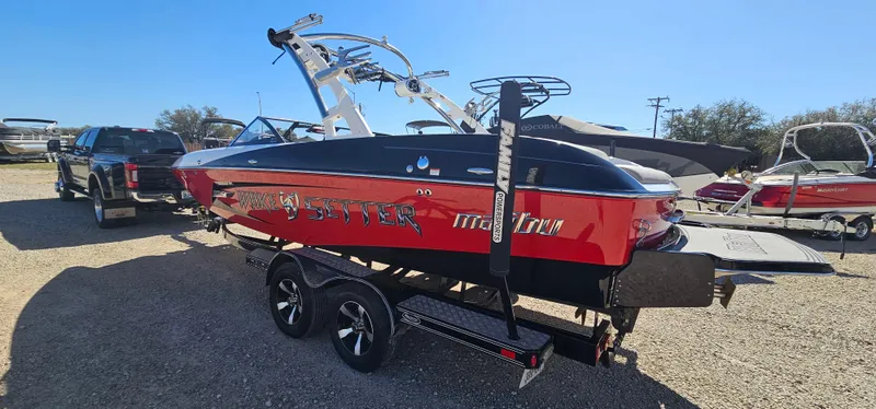 Slide: The Image of 2013 Malibu Wakesetter 23 MXZ boat on trailer, red and black design, parked outdoors. - 8