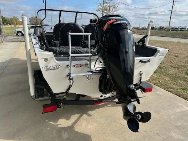 Slide: The Image of 2021 Tracker Pro Guide V 16 boat with outboard motor and ladder, parked on concrete. - 4