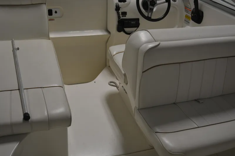 Slide: The Image of 1997 Sea Ray 240 Sundancer interior with white seating and steering wheel. - 21