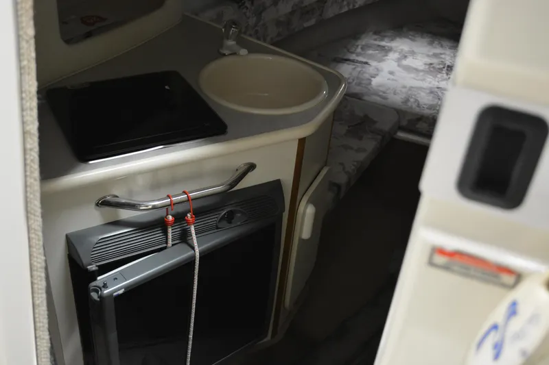 Slide: The Image of 1997 Sea Ray 240 Sundancer cabin interior with sink and compact fridge. - 28
