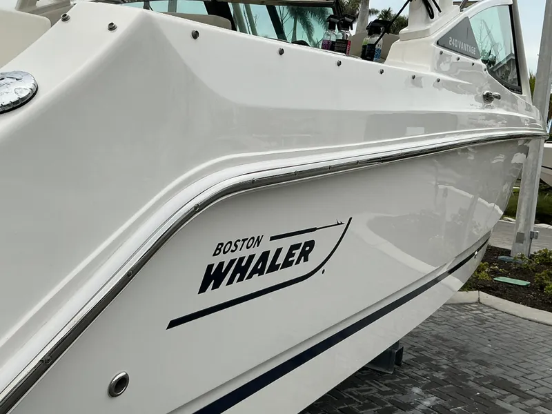 Slide: The Image of 2023 Boston Whaler 240 Vantage boat, sleek white exterior with logo, docked outdoors. - 15