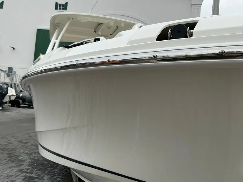Slide: The Image of 2023 Boston Whaler 240 Vantage boat, sleek white hull, docked outdoors. - 16