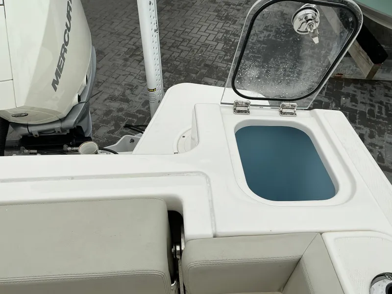 Slide: The Image of 2023 Boston Whaler 240 Vantage boat with open storage compartment and visible Mercury engine. - 33