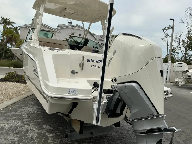 Slide: The Image of 2023 Boston Whaler 240 Vantage boat with Mercury outboard engine, docked outdoors. - 7