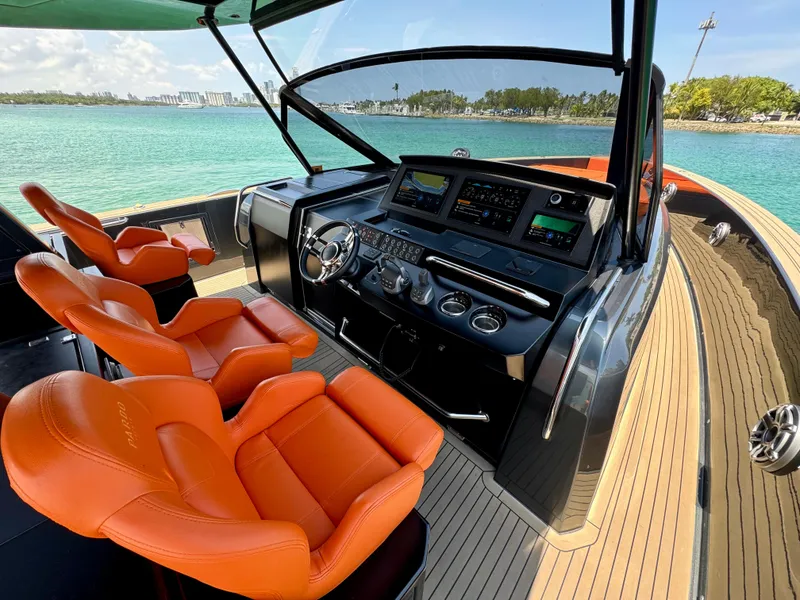 Slide: The Image of 2023 Pardo Yachts 50 cockpit with orange seats and modern controls, overlooking turquoise waters. - 12