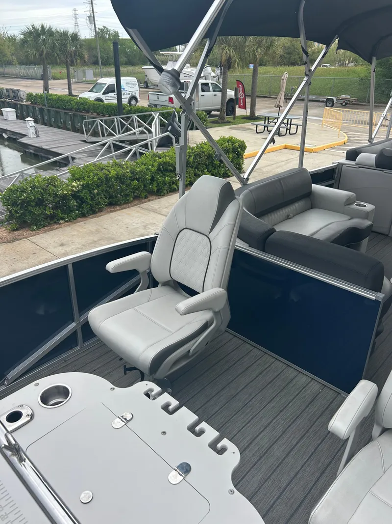 Slide: The Image of 2021 Avalon Catalina 24' boat interior with seating and table, docked near greenery. - 10