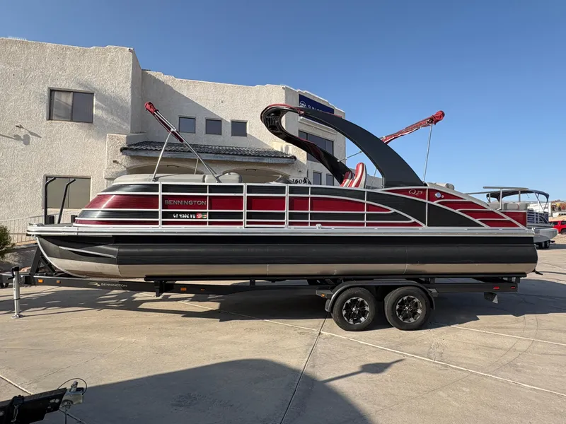 Slide: The Image of 2021 Bennington 25 QSBA IO pontoon boat on trailer, parked outdoors. - 0