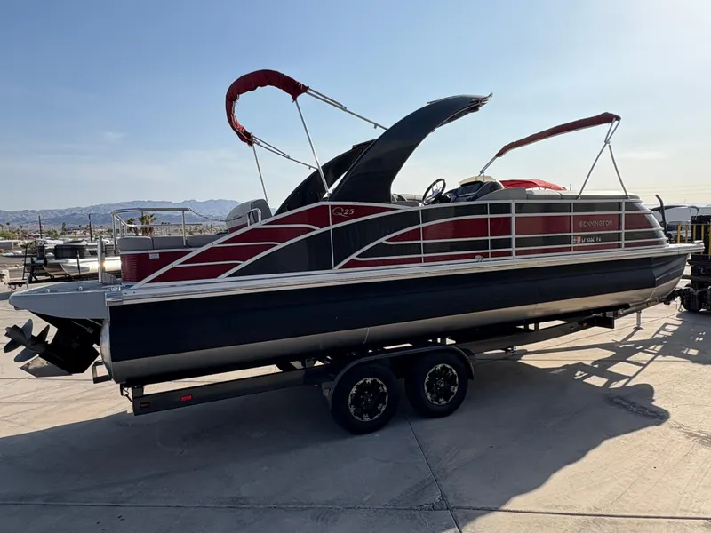 Slide: The Image of 2021 Bennington 25 QSBA IO pontoon boat on trailer, featuring sleek design and red accents. - 2