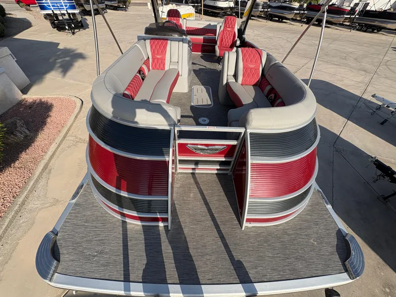 Slide: The Image of 2021 Bennington 25 QSBA IO pontoon boat with red and gray seating, docked on a sunny day. - 3