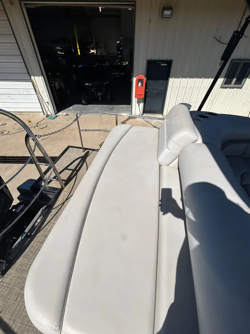 Slide: The Image of 2019 Harris Sunliner 240 boat with beige seating, docked near a garage. - 14
