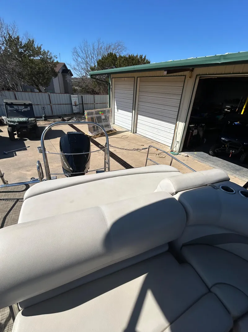 Slide: The Image of 2019 Harris Sunliner 240 pontoon boat parked near a garage under clear blue sky. - 16