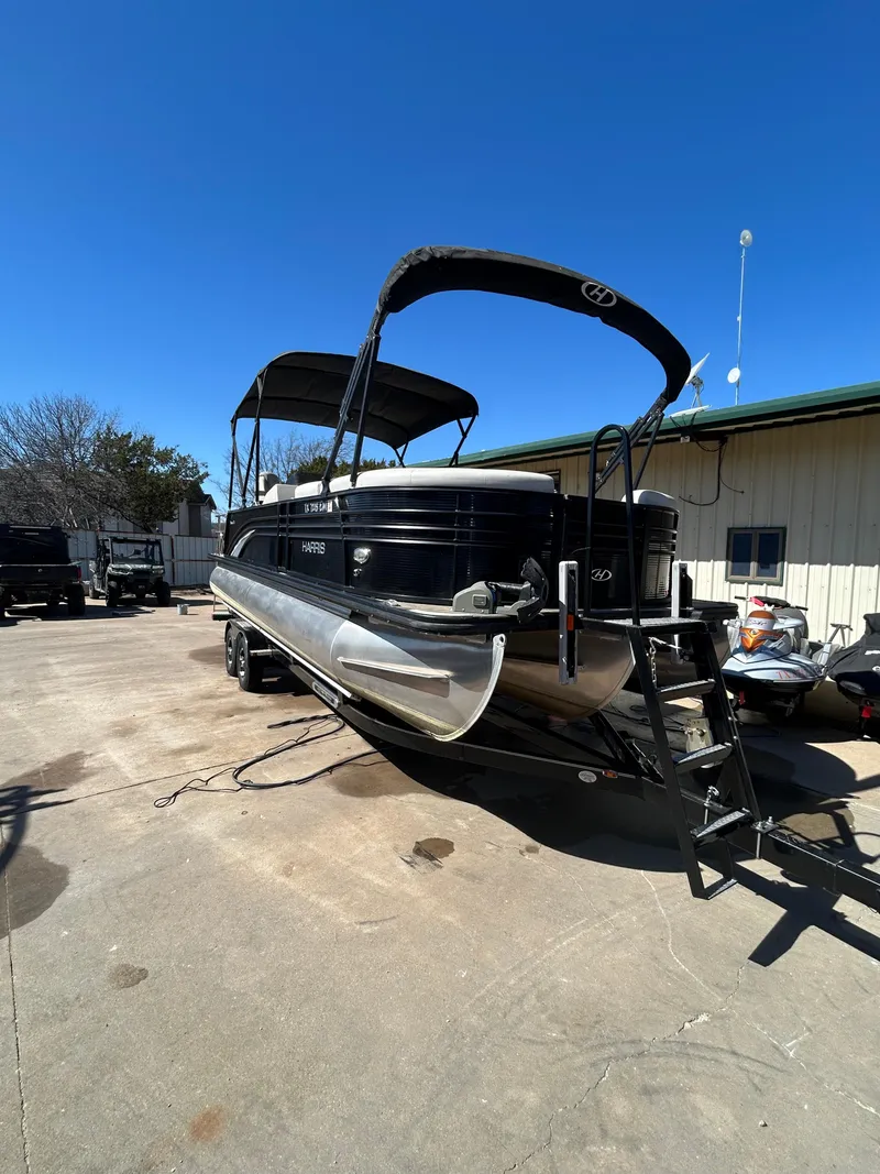 Slide: The Image of 2019 Harris Sunliner 240 pontoon boat parked outdoors under clear blue sky. - 2