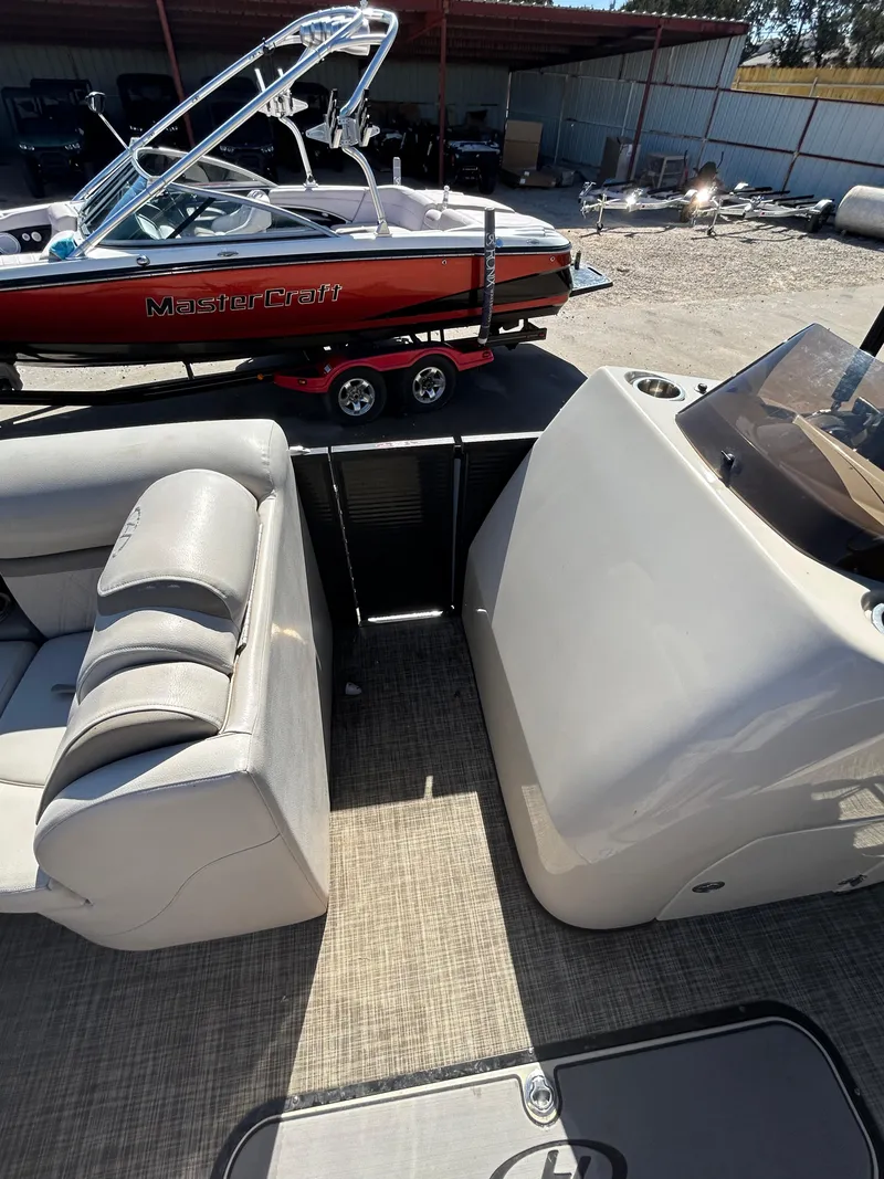 Slide: The Image of 2019 Harris Sunliner 240 interior with seating, adjacent to a red MasterCraft boat on a trailer. - 6