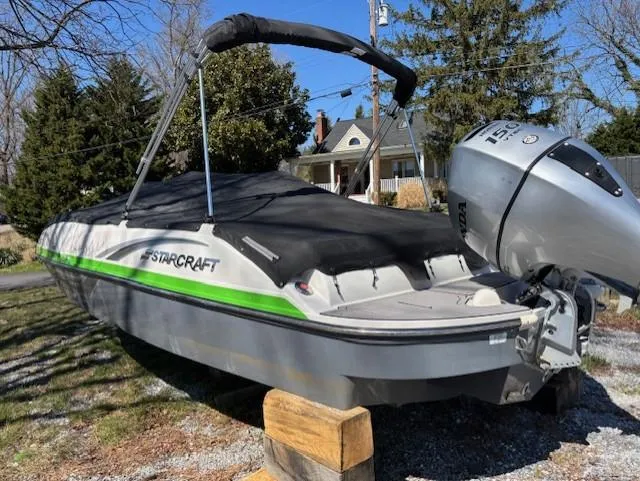 Slide: The Image of 2021 Starcraft MDX 211 E O/B boat with cover, parked on wooden blocks outdoors. - 8