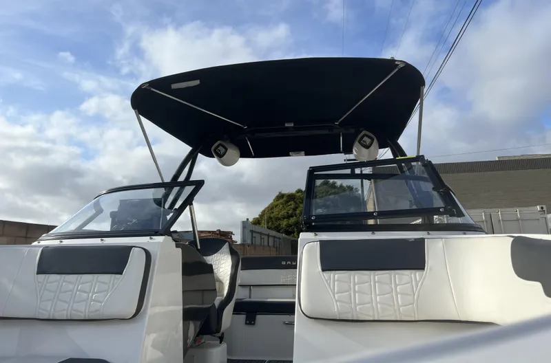 Slide: The Image of 2021 Bayliner VR5 Bowrider I/O boat with black canopy and white seating, under a cloudy sky. - 8