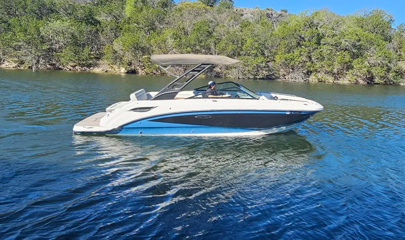 Slide: The Image of 2022 Sea Ray SDX 250 boat cruising on a serene lake with lush green trees. - 14