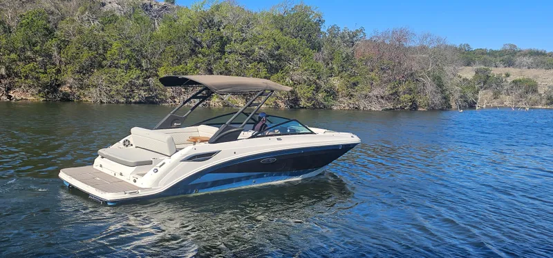 Slide: The Image of 2022 Sea Ray SDX 250 boat cruising on a serene lake with lush greenery. - 15